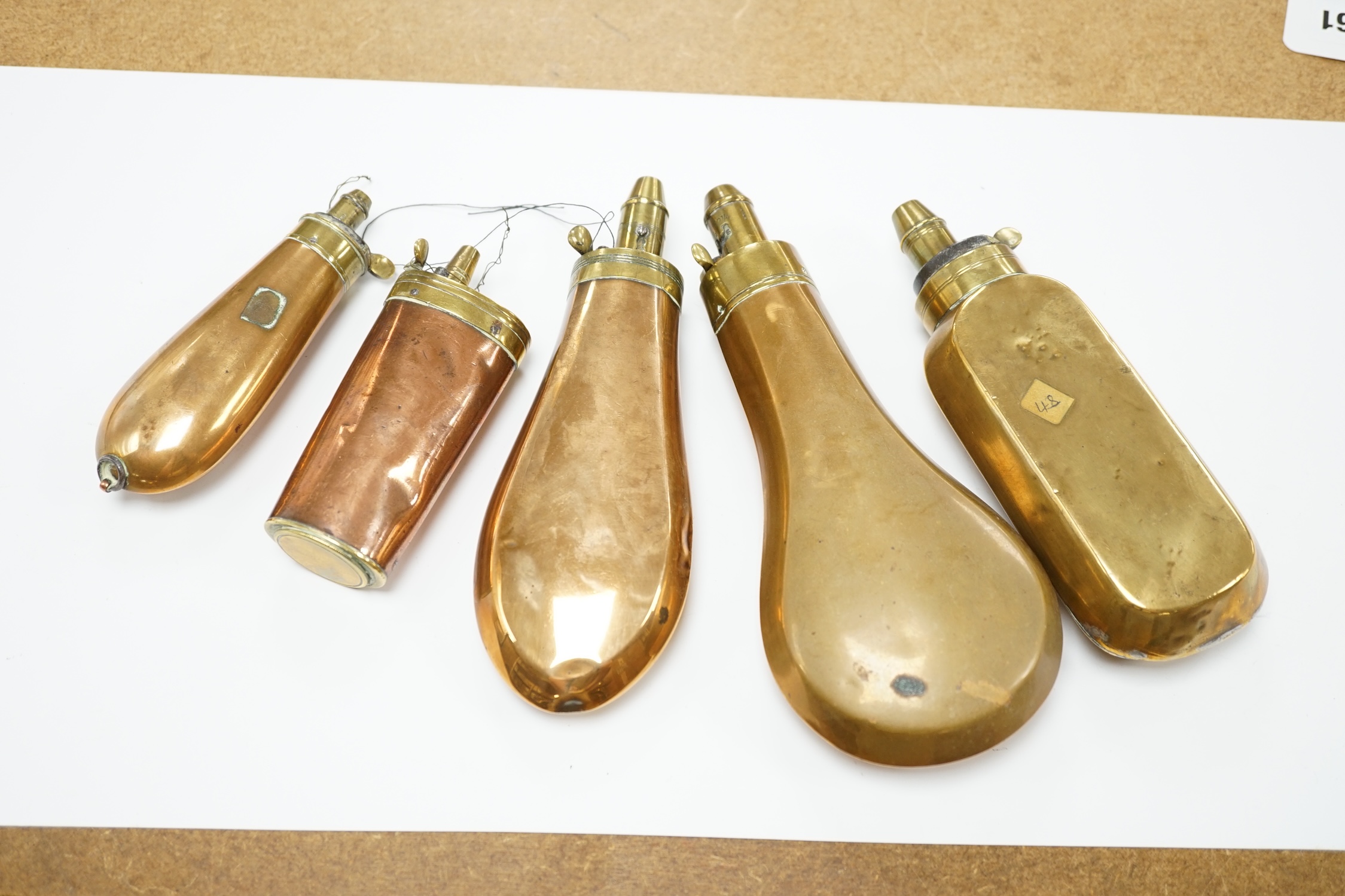 Five 19th century copper and brass powder flasks, all with plain copper bodies. Condition - fair